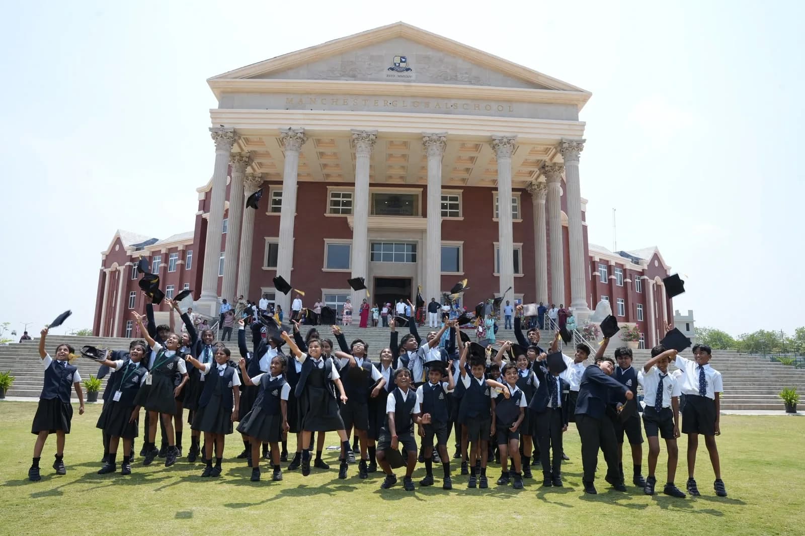 School students celebrating on the lawn in front of their school building