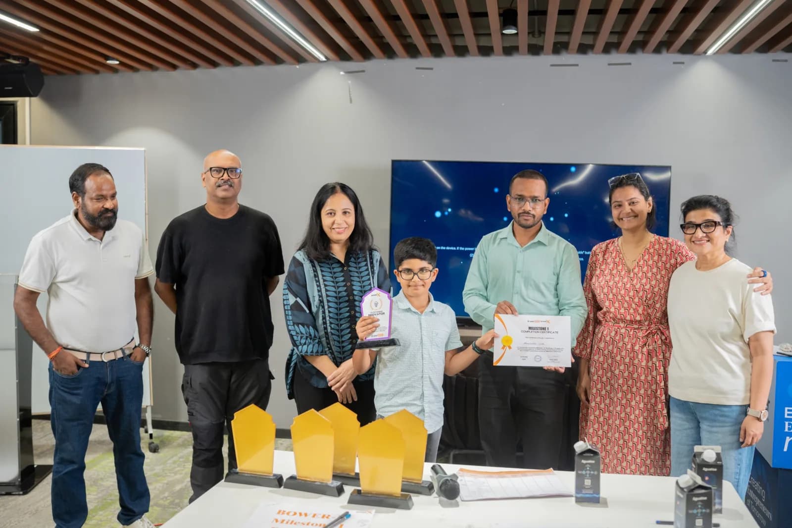 A student receiving a milestone completion certificate and innovator trophy
